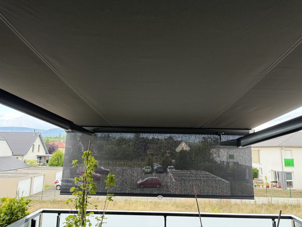Installation d’un store banne à bras croisés avec lambrequin enroulable à Herrlisheim à côté de Husseren-les-Châteaux.